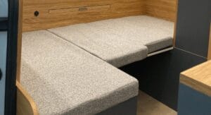 Banc rembourré avec coussins gris entre panneaux en bois clair.