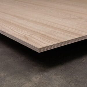 Panneau de bois clair sur béton avec grain visible.