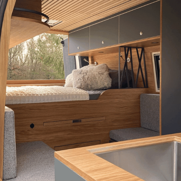 Aménagement Moderne de Camping-Car Aménagement intérieur d'un camping-car moderne avec lit en bois et rangements suspendus.