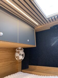 Intérieur moderne en bois clair avec placards, ventilateur et éclairage LED au plafond.