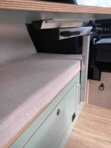 Banquette avec coussin intégré à un meuble en bois dans un espace de véhicule aménagé.