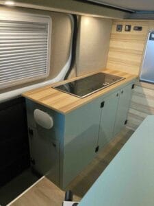 Espace cuisine moderne dans un véhicule avec plan de travail en bois, évier et placards.